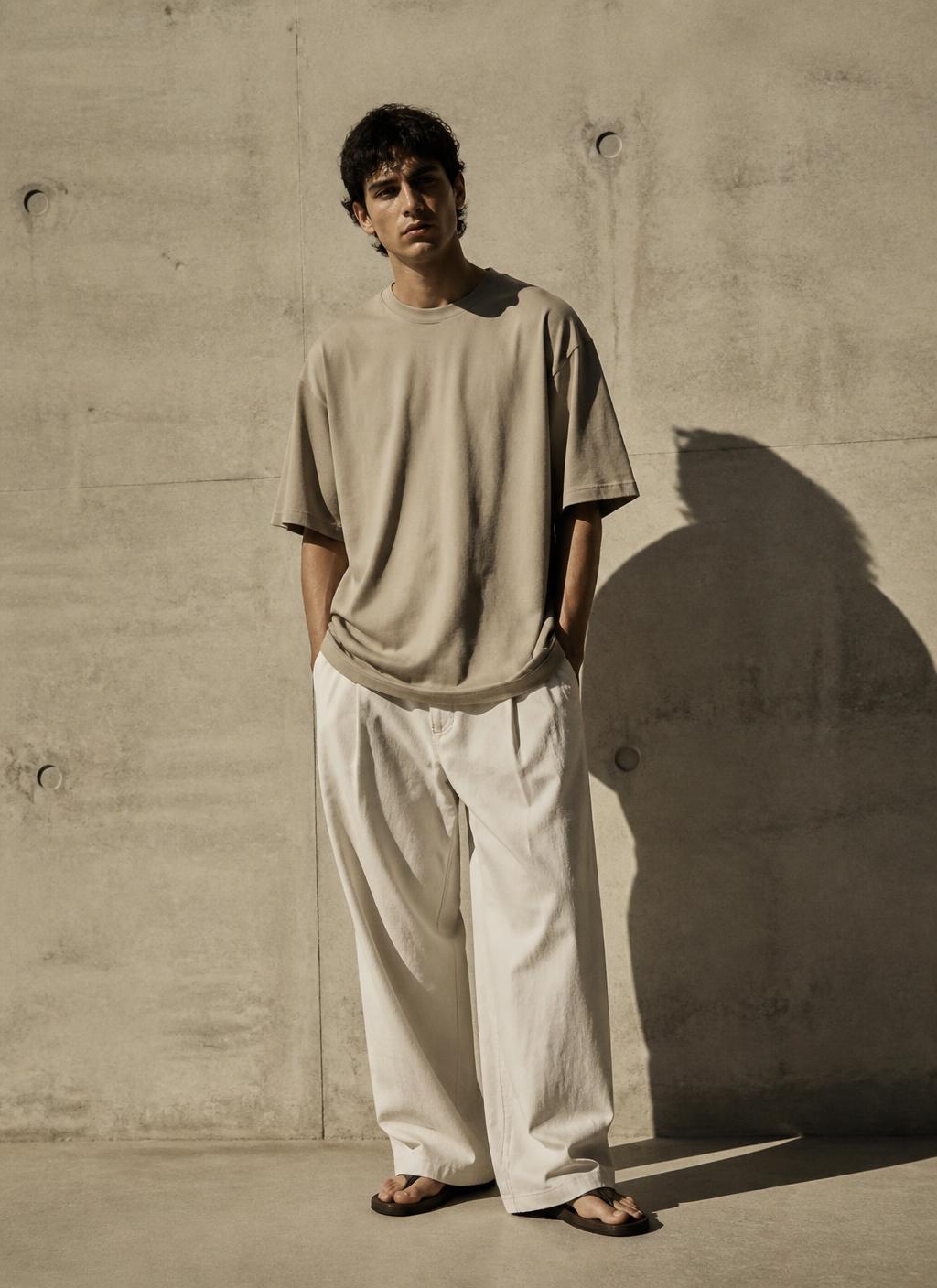 Modell in sandfarbenem Oversized-Shirt im harten Sonnenlicht