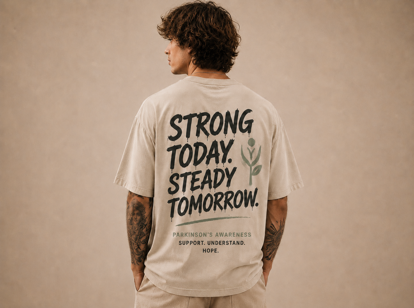 Rückenansicht eines sandfarbenen Oversize-Shirts mit dem Print „Strong today. Steady tomorrow.“ zum Thema Parkinson